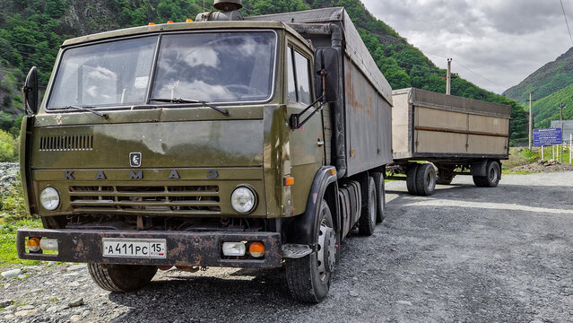 Green KamAZ-5320 truck with trailer and Russian license plates on a gravel road in the mountainous region near Vladikavkaz, historic Soviet truck, North Ossetia-Alania, Russia 11.05.25