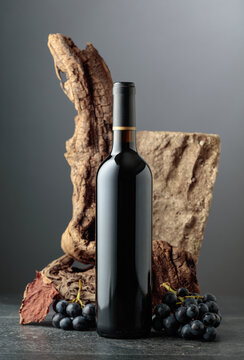 Bottle of red wine with stone, dried snags, and blue grapes.