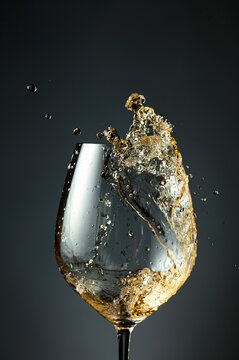 An image of white wine being splashed into a glass.