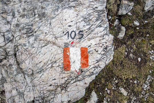 Trail marker 105 on rock indicating hiking path in Dolomites