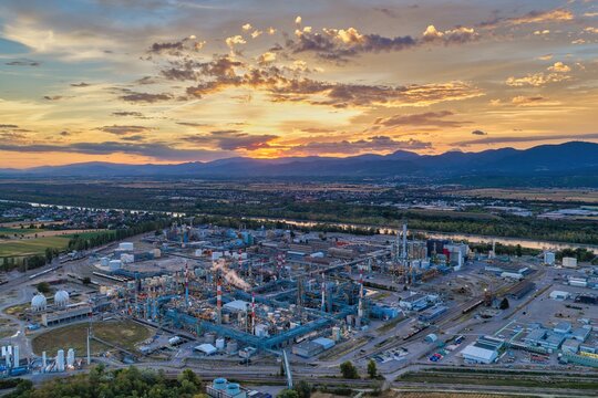 Aerial view of an industrial chemical plant with storage tanks and complex piping systems situated along the river at sunset in Bantzenheim, Grand Est, France.