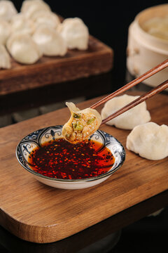 Traditional Handmade Seafood Dumplings with Spicy Chili Oil Dipping Sauce on Wooden Board