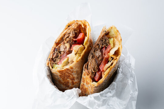 Detailed close-up of sliced beef shawarma wrap with fresh vegetables