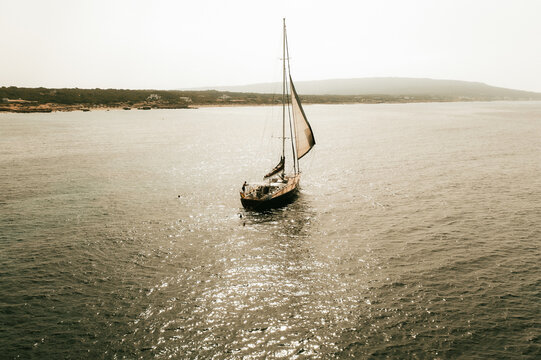Aerial view of a sailboat sailing on the calm Mediterranean sea near the coast of Formentera, Balearic Islands, Spain.