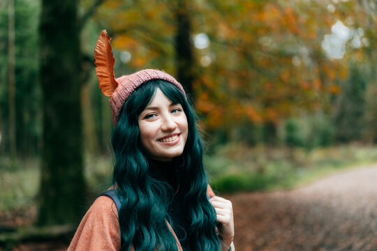 Hipster Woman in hat with big fallen leaf wrapped in warm Shawl Poncho enjoying autumn walk in forest. Feeling harmony, reunion with nature. Relaxing, Relaxing, mental recovery. Indie boho vibes.