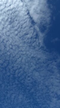 Beautiful cirrocumulus clouds moving across vibrant blue sky on sunny day