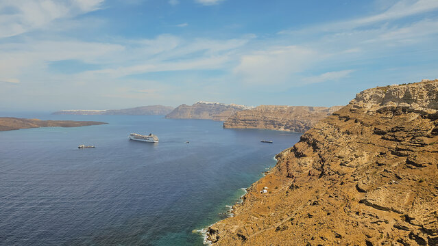 High angle view of volcanic caldera cliffs with cruise ship sailing in deep blue sea bay at Santorini island Greece landscape stock photo