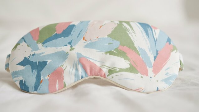 Fabric sleep mask with pastel floral brushstroke pattern on white background