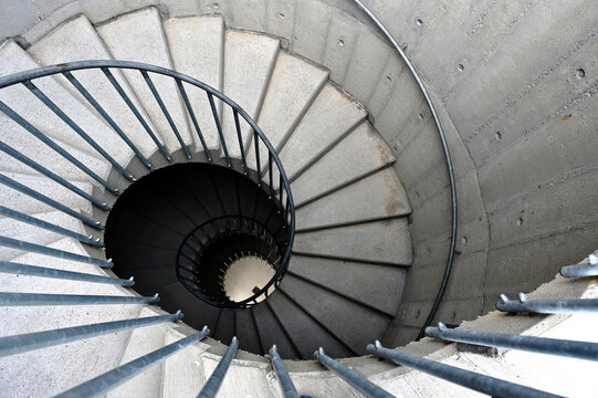 concrete spiral exterior stair in diminishing perspective view. looking down. galvanized picket guard rail. circular inner core. concrete texture. architecture and construction concept.
