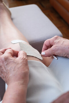 Applying medical tape to senior knee for recovery