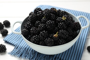 Ripe blackberries in bowl and towel on white wooden table, closeup © New Africa
