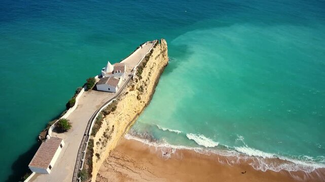 Picturesque chapel of nossa senhora da rocha standing on a rocky cliff promontory overlooking the turquoise atlantic ocean on the sunny coastline of algarve, portugal