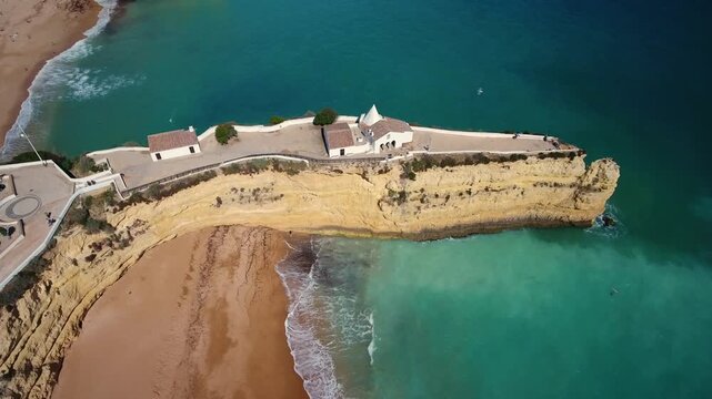 Scenic aerial view showing the chapel of nossa senhora da rocha perched on a spectacular cliff promontory, surrounded by the atlantic ocean and sandy beaches in algarve, portugal