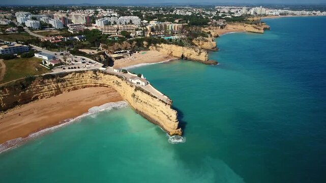 Majestic aerial view of the iconic chapel of nossa senhora da rocha, perched on a dramatic cliff overlooking the turquoise atlantic ocean and the beautiful sandy beaches of algarve, portugal