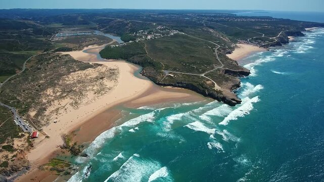 Spectacular aerial perspective of the atlantic ocean waves crashing on amoreira beach, where the aljezur river meets the sea along the stunning vicentina coast in algarve, portugal