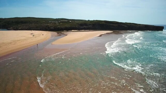 Stunning aerial perspective of the atlantic ocean waves washing over the golden sand at amoreira beach, where the aljezur river meets the sea on the picturesque vicentina coast in portugal