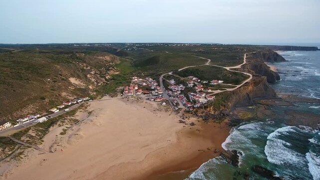 Aerial footage showing the scenic village of monte clerigo on the sandy shores of the atlantic ocean, nestled within the beautiful landscape of costa vicentina in aljezur, portugal