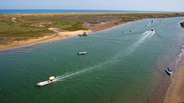 Aerial view of several motorboats and tourist water taxis sailing on the green waters of the ria formosa lagoon, a stunning natural park and popular summer destination in algarve, portugal