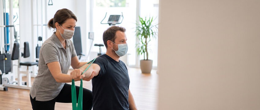 Physical therapist guides adult patient through rehabilitation exercise, demonstrating movement to support injury recovery, mobility, strength, patient care and physical therapy treatment.