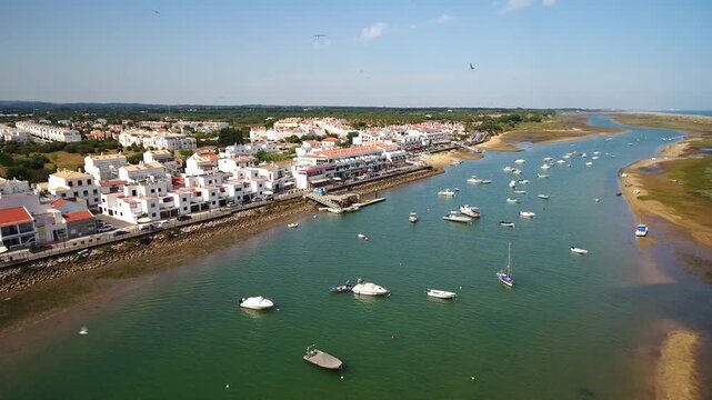 Drone view flying over the picturesque coastal fishing village of cabanas de tavira in the algarve, portugal, showing the beautiful waterfront, ria formosa lagoon, and anchored boats