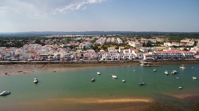 Aerial view moving sideways over the ria formosa lagoon, showing the beautiful waterfront of cabanas de tavira, a traditional fishing village in the sunny algarve region of southern portugal