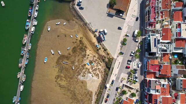 Zenithal aerial view showing the waterfront town of cabanas de tavira with boats moored along the pier and the shore of the ria formosa lagoon, a stunning tourist destination in the algarve