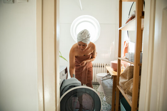 Woman loading washing machine in small bathroom