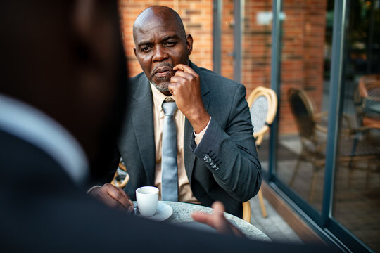 Thoughtful businessman listening during meeting at outdoor cafe
