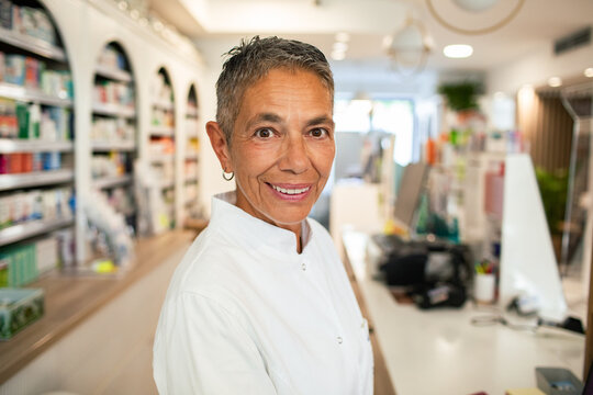 Smiling pharmacist at counter in modern pharmacy