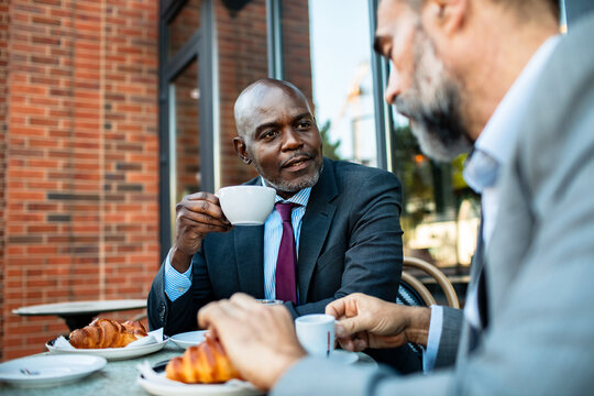 Two businessmen talking over coffee at outdoor cafe
