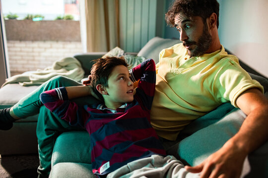 Father and son talking on living room sofa