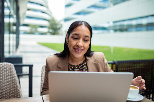 Smiling businesswoman working on laptop at outdoor cafe