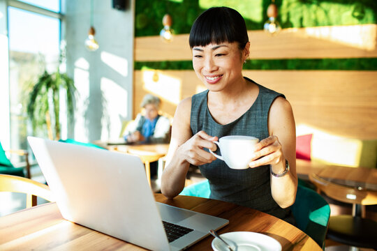 Smiling woman working on laptop at cafe