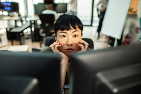 Woman concentrating on dual monitors in open office