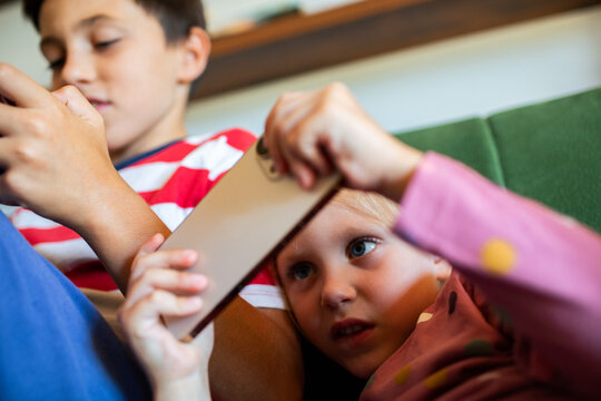Brother and sister using smartphones on couch at home