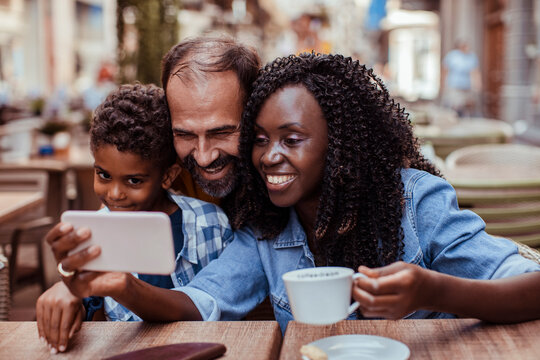 Smiling family taking selfie at outdoor cafe