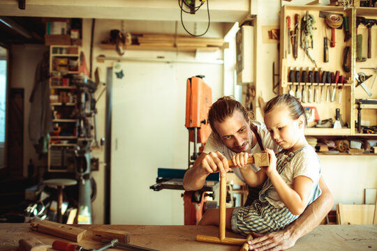 Father teaching daughter woodworking in home workshop