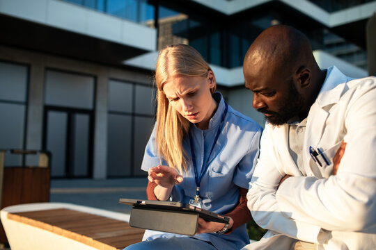 Healthcare professionals reviewing patient data on tablet outside hospital