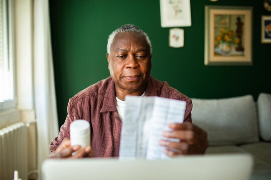 Senior man reading medication instructions at home