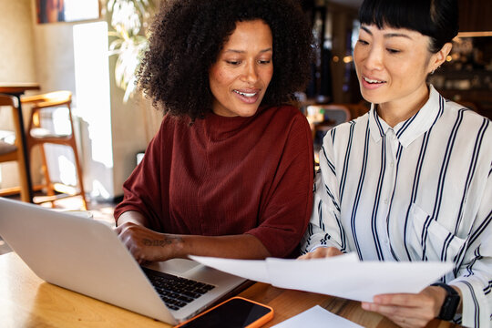 Two coworkers collaborating with laptop in cafe