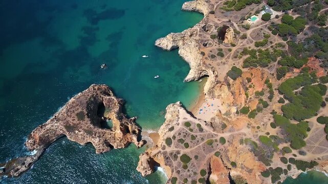 Spectacular aerial perspective of the rugged algarve coastline in portugal, featuring beautiful beaches, turquoise ocean water, dramatic cliffs, and natural sea arches under a sunny sky