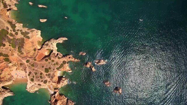 Dramatic aerial view flying over the stunning algarve coastline in portugal, revealing secluded beaches, golden cliffs, and the beautiful turquoise waters of the atlantic ocean