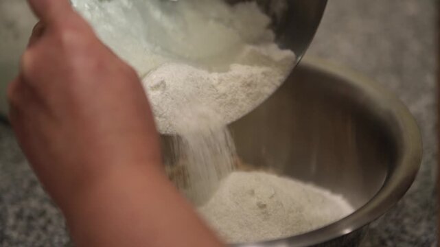 Professional baker pouring flour and sugar from one bowl to another with a spoon, showing a crucial step in the preparation of sweet dough for cakes and other confections in a bakery