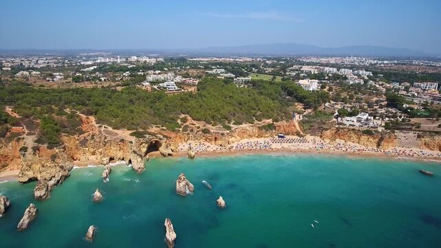 Breathtaking aerial footage capturing the stunning coastline of praia da rocha in portimao, showing dramatic cliffs, golden sand beaches, and unique rock formations rising from the turquoise ocean