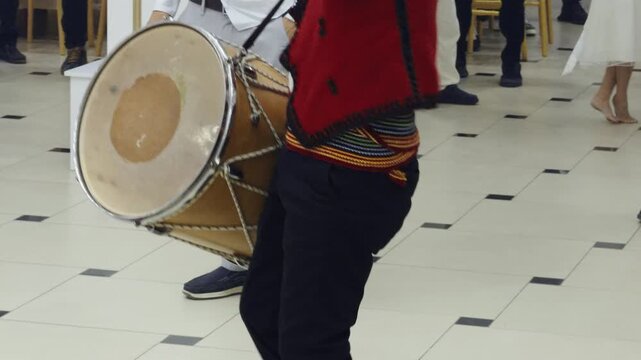 Traditional musician plays a large tupan drum during a lively wedding in northern Albania, providing energetic folk rhythms for guests celebrating Albanian customs, marriage, and community traditions.