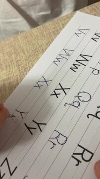 Child hand tracing dotted capital letter Y with pen on handwriting practice worksheet worksheet close up vertical stock video. High quality 4k footage