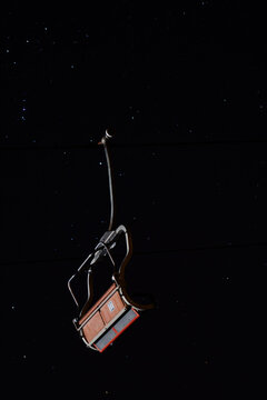 Empty ski lift chair silhouetted against starry night sky