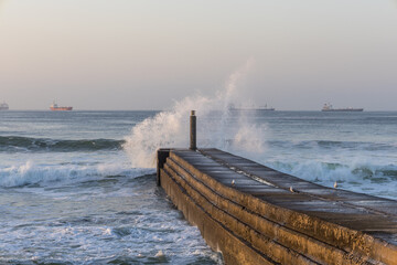 Sunrise waves crashing dock with cargo ships in cascais © ANTONIO COSTA