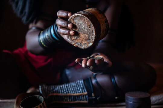 Himba woman preparing traditional otjize powder in Namibia