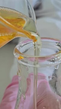 Pouring liquid into a small glass bottle in a kitchen setting